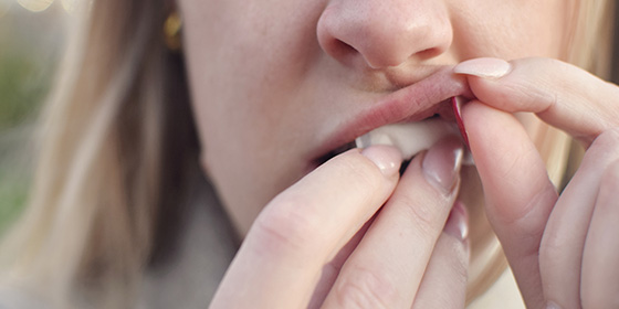 eine Frau schiebt sich gerade einen Nikotinbeutel unter die Lippe